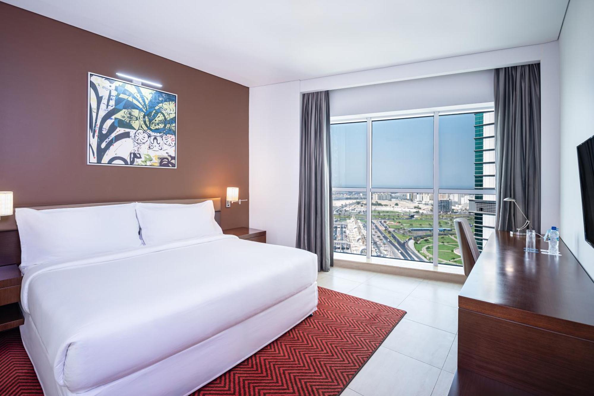 Eckzimmer mit Balkon, Kingsize-Bett und Blick auf die Skyline