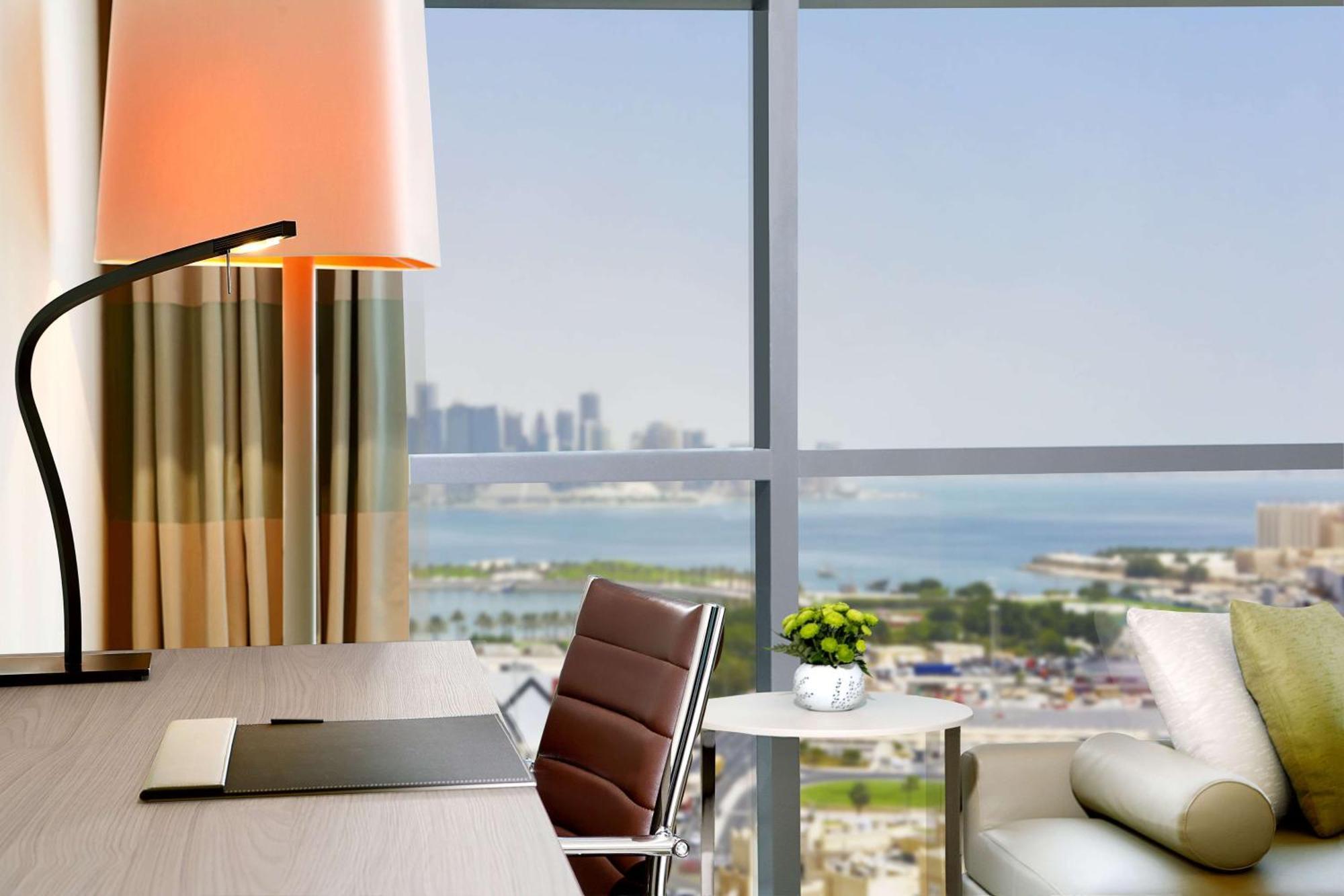 Zimmer mit Kingsize-Bett und Blick auf das Meer und die Skyline
